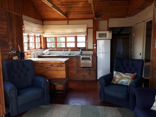 a kitchen with two blue chairs and a refrigerator at The Tin Shack in Underberg