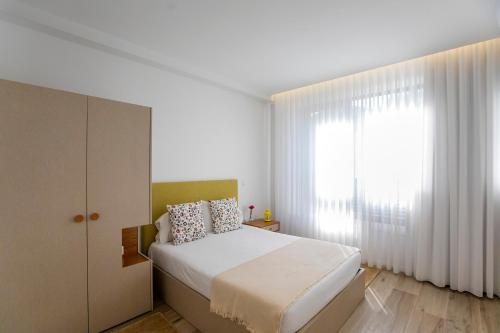 um quarto com uma cama branca e uma janela em 2 Bedroom Cosy Flat em Porto