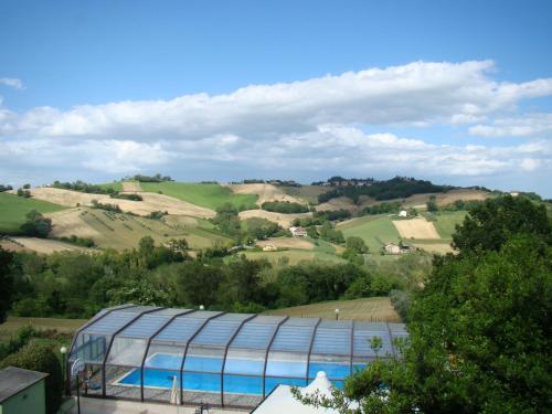 a glass building with a view of the rolling hills at Agriturismo Vecchio Gelso in Ortezzano