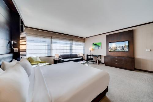 a bedroom with a large white bed and a living room at Jet Luxury at The Vdara in Las Vegas