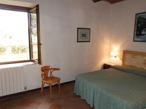 - une chambre avec un lit, une chaise et une fenêtre dans l'établissement Agriturismo La Torretta, à Castagneto Carducci