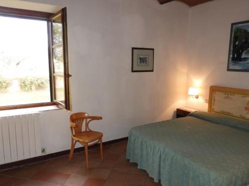 a bedroom with a bed and a chair and a window at Agriturismo La Torretta in Castagneto Carducci