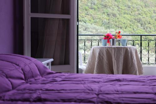 Una cama púrpura con una mesa con flores en el balcón en Natasa and Spiros, en Paleokastritsa