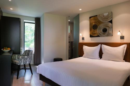 LompretにあるLa Ferme Blanche, The Originals Relaisのベッドルーム(大きな白いベッド1台、椅子付)