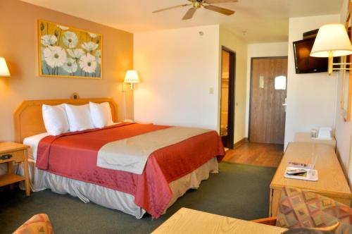 a hotel room with a bed with a red blanket at Wingate by Wyndham Farmington NM in Farmington