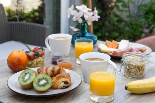 a table topped with plates of breakfast foods and orange juice at La Ferme Blanche, The Originals Relais in Lompret