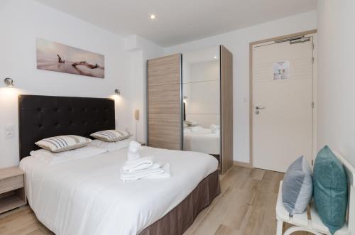 une chambre avec un grand lit blanc et une salle de bain dans l'établissement Cap Nègre Hôtel, au Lavandou