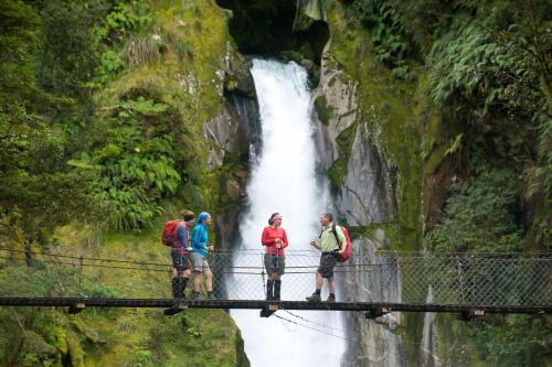 a group of people standing on a suspension bridge over a waterfall at Fiordland Lodge in Te Anau