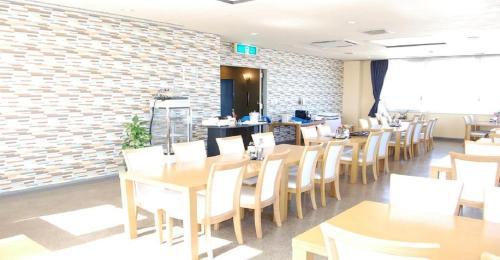 ein Restaurant mit Holztischen und -stühlen und Ziegelwand in der Unterkunft Seagrande Shimizu Station Hotel / Vacation STAY 8198 in Shizuoka