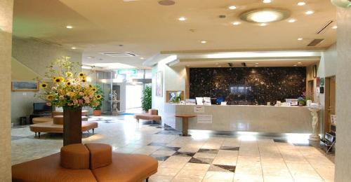 Seagrande Shimizu Station Hotel / Vacation STAY 8208 في شيزوكا: لوبي مع منطقة انتظار مع مزهرية ورد في الوسط