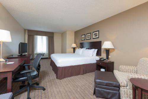 オーロラにあるHoliday Inn Aurora North - Naperville, an IHG Hotelのベッド、デスク、椅子が備わるホテルルームです。