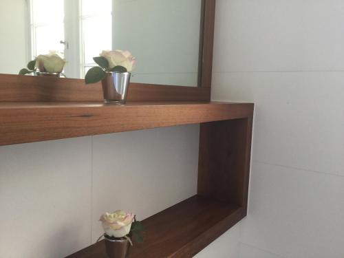 a shelf with a mirror and a vase with flowers at The Lake Lodge, Wansfell Holme, Windermere in Ambleside