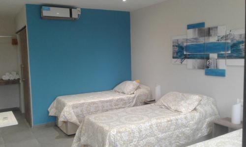Habitación con 2 camas y pared azul en Hotel El Recreo en General Roca