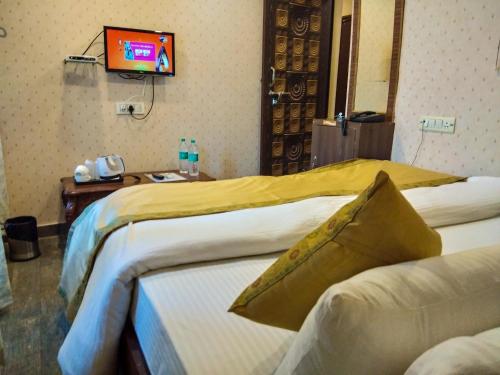 a hotel room with two beds and a tv on the wall at Dwivedi Hotels Palace On Steps in Varanasi