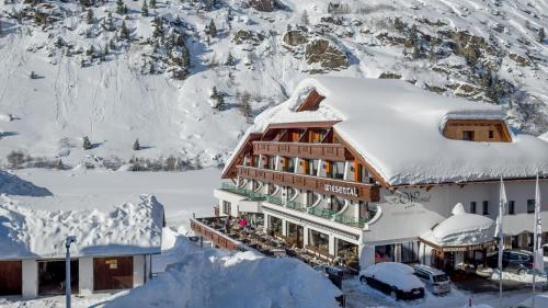 a building covered in snow with a mountain in the background at Hotel Wiesental in Obergurgl