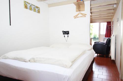 1 dormitorio con 1 cama blanca y 1 silla en Park Nieuwgrapendaal, en Terwolde