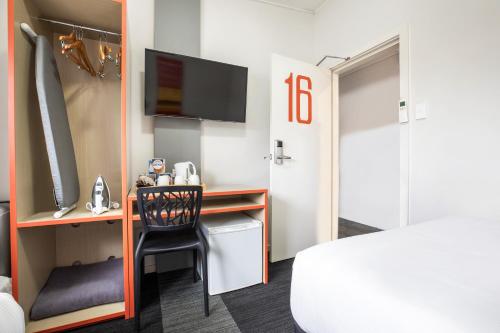 a hotel room with a bed, chair and a mirror at Villawood Hotel in Villawood
