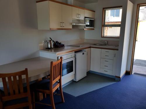 
a kitchen with a table and chairs and a microwave at The Anchor Inn Beachfront Motel in Kaikoura

