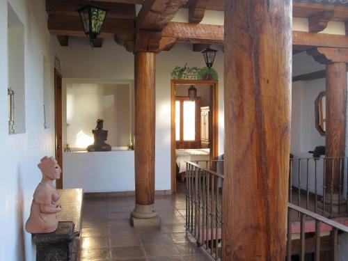 pasillo con columnas de madera y habitación con espejo en Hotel Estancia de la Era B&B en Pátzcuaro