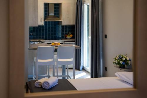 a kitchen with two white chairs and a table in a room at Dorotea Luxury Rooms in Ipsos