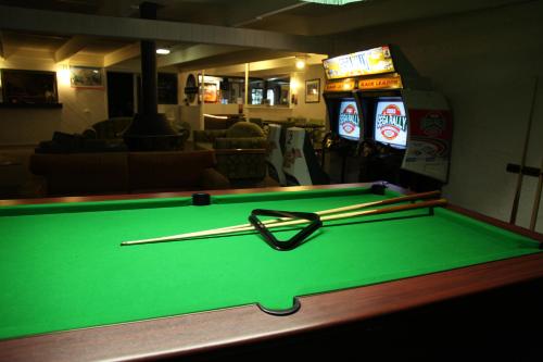 a pool table with two cuesticks and two soda machines at Siesta Villa in Jindabyne