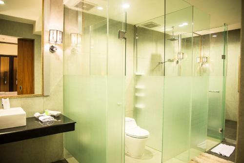 a bathroom with a toilet and a glass shower at Hotel Diamond in Solo