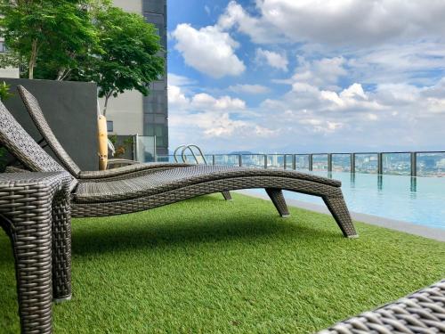 a wicker bench sitting on the grass near the water at CoZy Suite @ PJ & Sunway(2 Bedroom) in Petaling Jaya