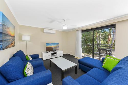 uma sala de estar com sofás azuis e uma televisão em Flynns Beach Resort em Port Macquarie