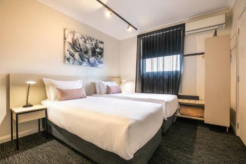 a hotel room with two beds and a window at Nightcap at Hendon Hotel in Adelaide