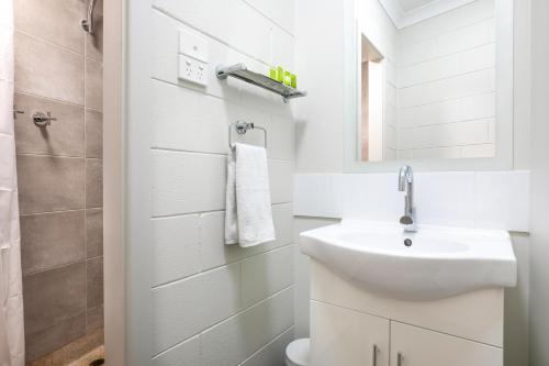 a white bathroom with a sink and a mirror at Nightcap at Hendon Hotel in Adelaide