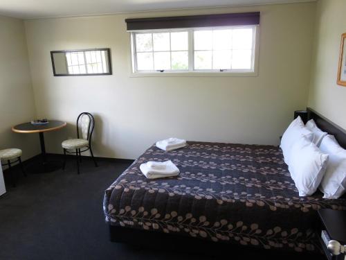 a room with a bed and a table and a window at Admirals Motor Lodge in Blenheim