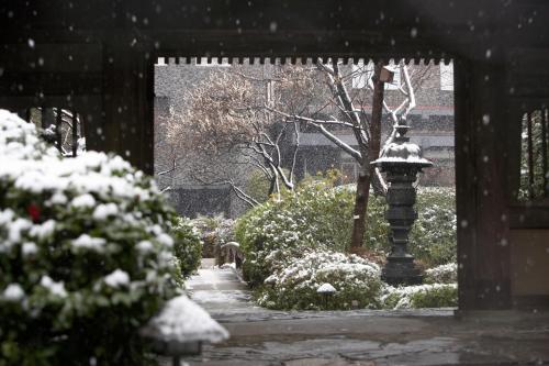 a snow covered garden with a light pole and bushes at The Prince Sakura Tower Tokyo, Autograph Collection in Tokyo
