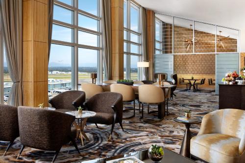 a hotel lobby with chairs and tables and windows at Fairmont Vancouver Airport In-Terminal Hotel in Richmond