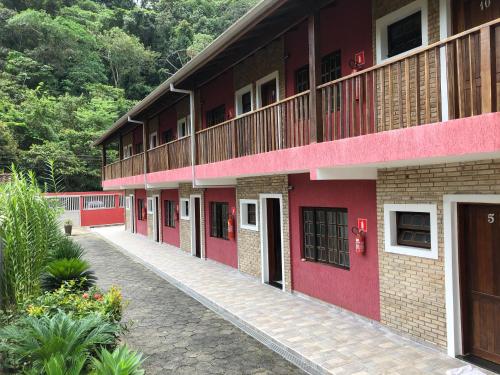 a red building with a walkway in front of it at Chalés Buriti in Caraguatatuba