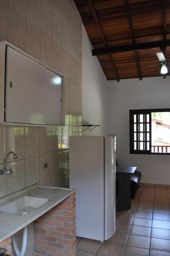 a kitchen with a white refrigerator in a room at Chalés Buriti in Caraguatatuba
