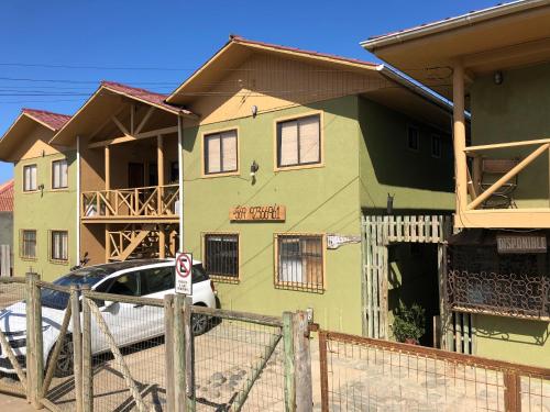a green house with a car parked in front of it at Delfín Apart in Pichilemu