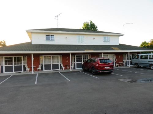 a red car parked in a parking lot in front of a building at Admirals Motor Lodge in Blenheim