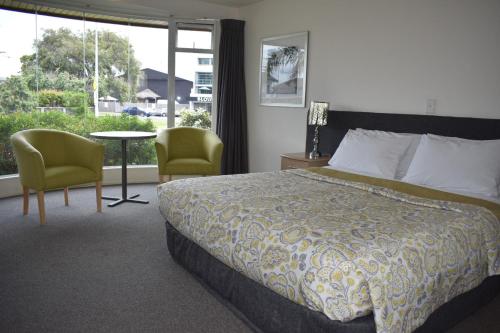 a hotel room with a bed and a table and chairs at Baywatch Motor Inn in Mount Maunganui