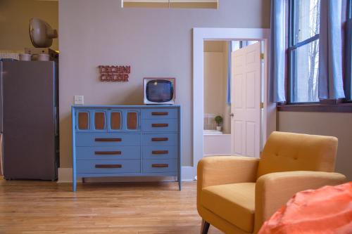 a room with a blue dresser with a tv and a chair at School 31 Lofts in Rochester