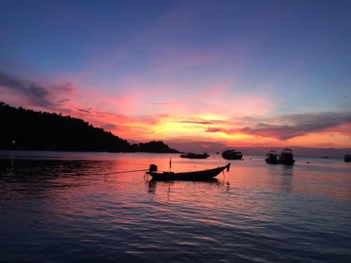 a person in a boat in the water at sunset at Field-D House in Koh Tao