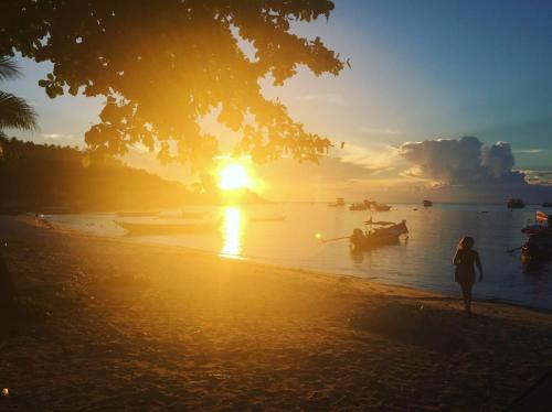 a person standing on a beach with boats in the water at Field-D House in Koh Tao
