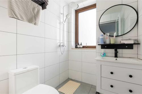 a white bathroom with a toilet and a mirror at Haikou Meilan District · Xixili Locals Apartment 00175140 in Haikou