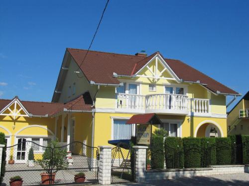 ein gelbes Haus mit einem Zaun davor in der Unterkunft Villa Jäger in Vonyarcvashegy