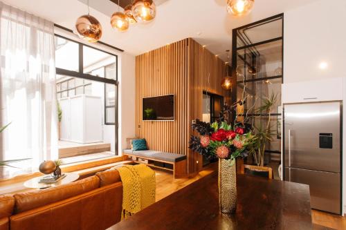 a living room with a couch and a table with flowers at Auckland City Spacious Loft - 4 Bedrooms & 2 Free Car Parks in Auckland