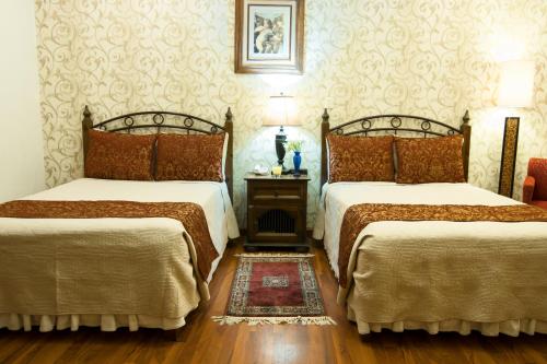 a room with two beds and a table with two lamps at Hotel Casa Divina Oaxaca in Oaxaca City