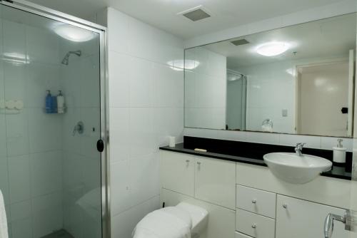 een witte badkamer met een wastafel en een spiegel bij 91 Liverpool Street, World Tower in Sydney