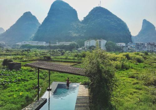 een persoon in een zwembad met bergen op de achtergrond bij Yangshuo Sudder Street Guesthouse in Yangshuo