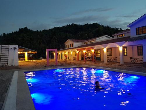 a person swimming in a swimming pool at night at Lazuli Resort in San Vicente