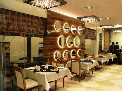 a restaurant with tables and chairs and mirrors on the wall at HOTEL EXCELLENCY in Bhubaneshwar