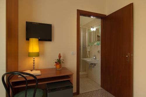 a room with a desk with a lamp and a sink at Mio Hotel Firenze in Florence